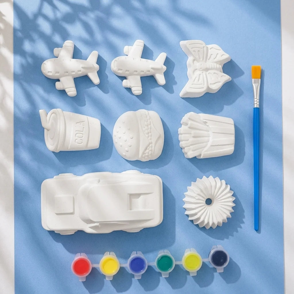 Planes and fast food Plaster of Paris mix kit — 8 white figures with 6-colour paint strip and brush on light blue background