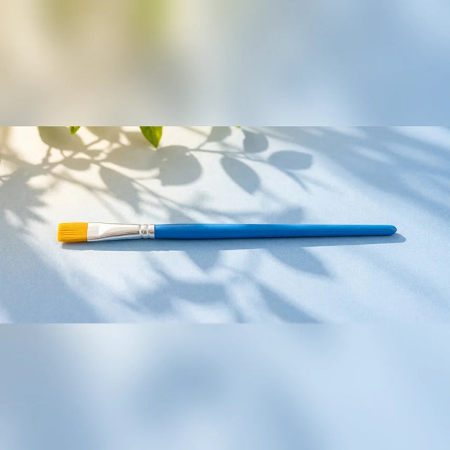 Blue kids paint brush with golden bristles on light blue background
