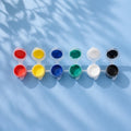 Six-colour kids paint strip with red, yellow, blue, green, white and black pots on light blue background