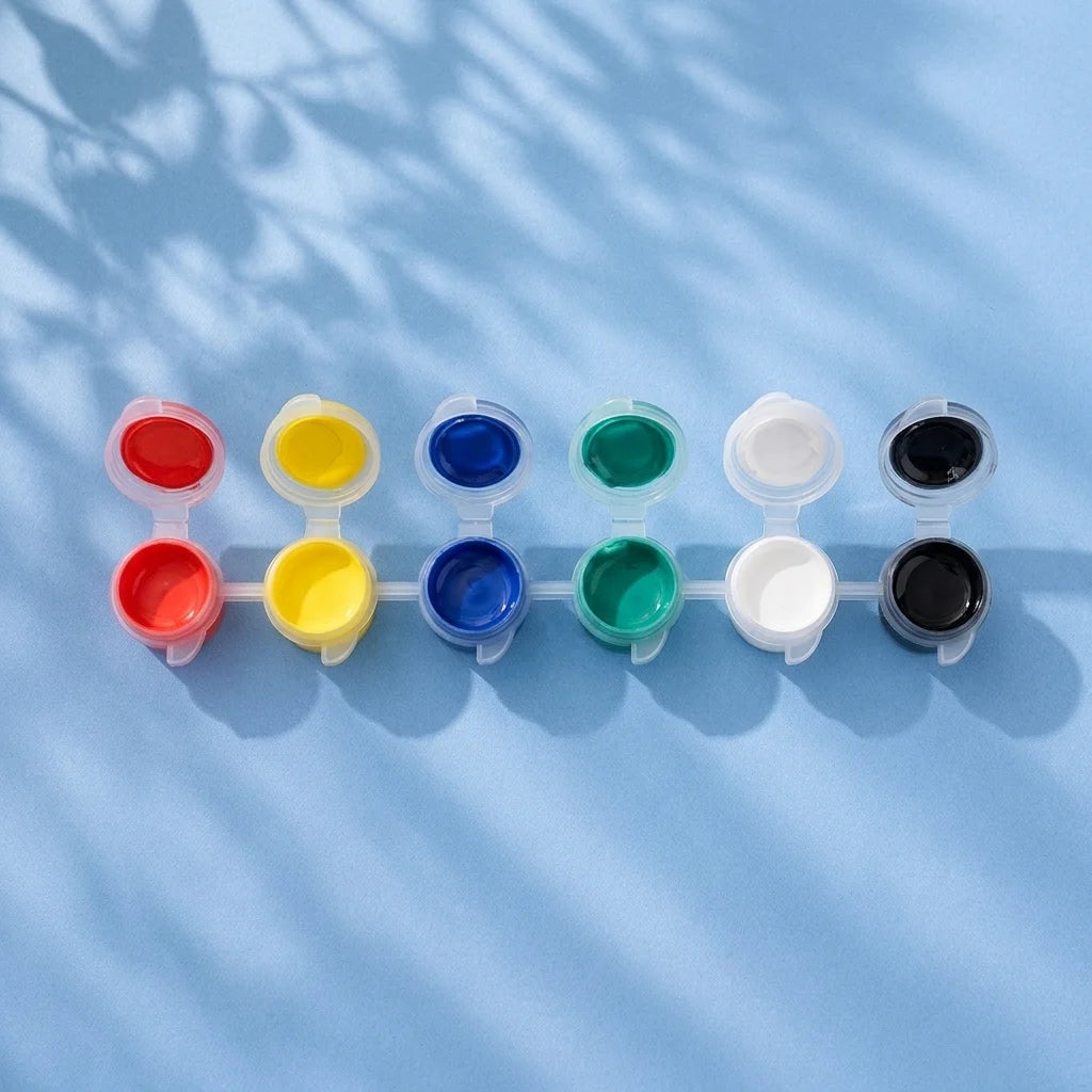 Six-colour kids paint strip with red, yellow, blue, green, white and black pots on light blue background